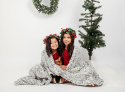 Two children snuggle under blanket in holiday photo