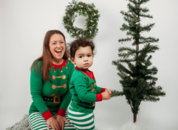 Toddler and mother gather around christmas tree for holiday photo