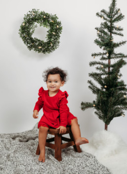 Toddler poses for holiday photo near christmas tree