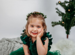 Toddler in green dress poses for holiday photograph