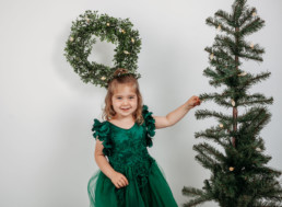 Toddler touching a christmas tree and smiling in photograph