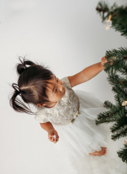 Young child touches christmas tree in studio photo