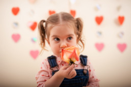 Toddler sits for in studio photo shoot in Pasadena, California with valentine day themed props, roses