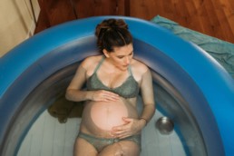 Thirty somthing woman labors in blue pool during water birth at home birth