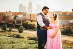 Pregnant woman and expecting father embrace and laugh while mother holds baby in her belly