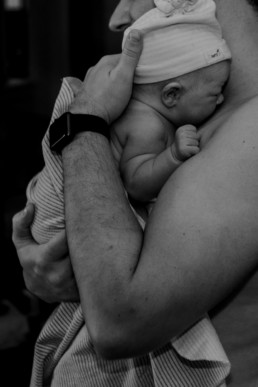 Photo of dad holding newborn baby skin to skin immediately following childbirth