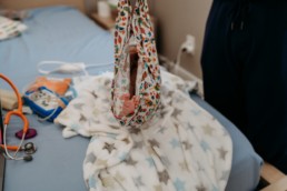 Image of baby feet while baby is in midwife's fabric to be weighed at a homebirth.