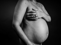 Image of pregnant bare belly. Mother drapes her arm across her body
