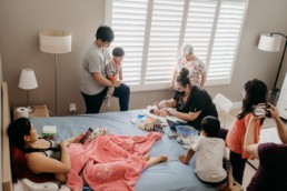Family gathers around midwife who is doing a newborn on baby at home